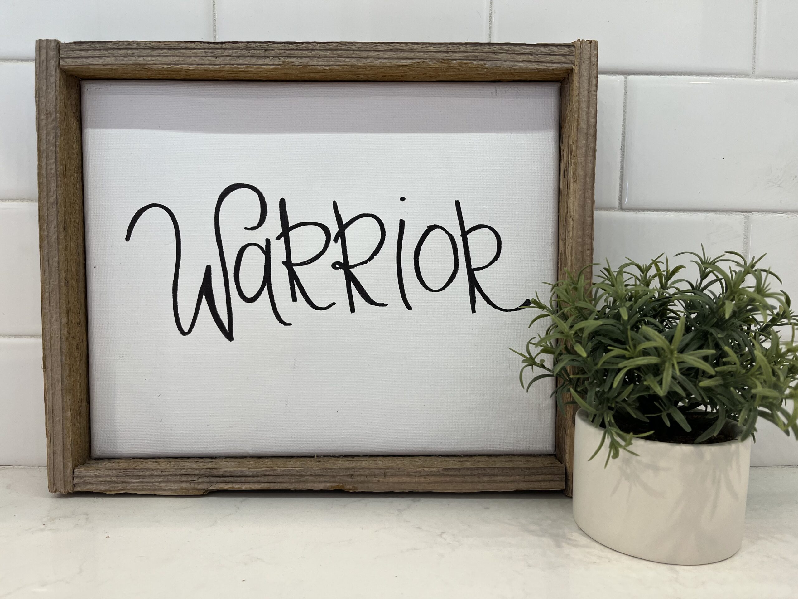 decoration with the word "warrior" and a small succulent against a white backdrop